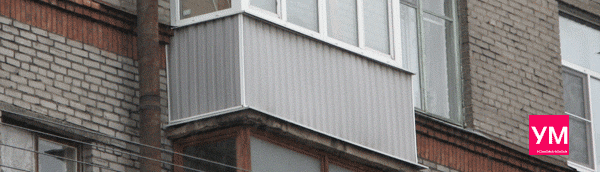 Балкон после остекления и полной отделки. Снаружи обшит металлическим профильным листом серого цвета.