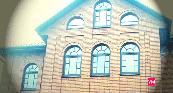 Арочные пластиковые окна с декором в коричневом цвете. Установлены в кирпичном загородном доме
