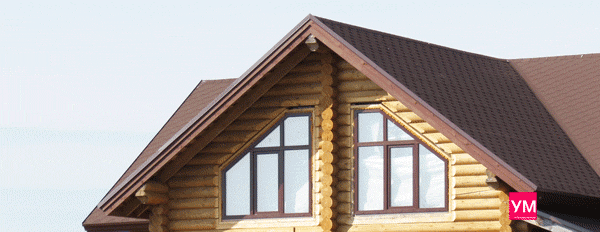 Бревенчатый дом с установленными цветными окнами коричневого цвета