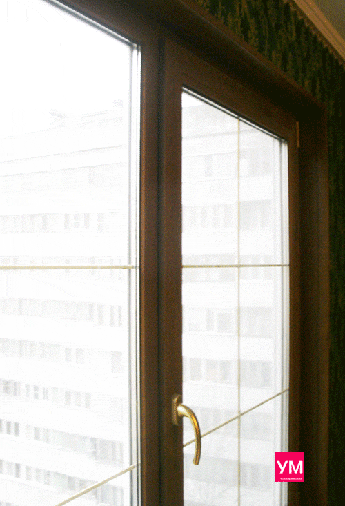 Золотые шпросы, декоративные профиля, установленые в стеклопакете. Видно красивое ламинированное окно под дерево