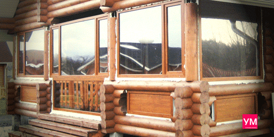 Веранда в доме из оцилиндрованного бревна с установленными на ней пластиковыми окнами цвета золотой дуб