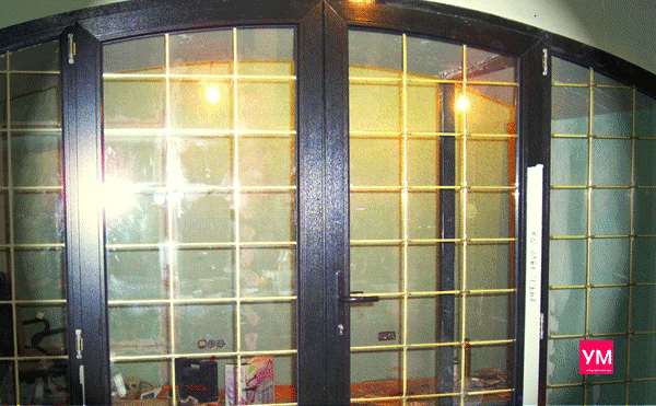 Арочная двухстворчатая верандная дверь из пластиковых профилей цвета чёрный дуб. Стеклопакет сделан со шпросами, с мелкой расстекловкой.